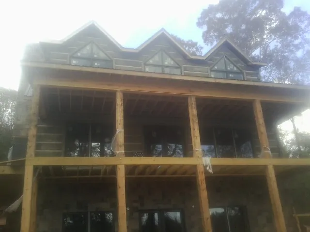 Dormers and porch framing on a large log home under construction — Roof Coating work by our crew in Stockdale