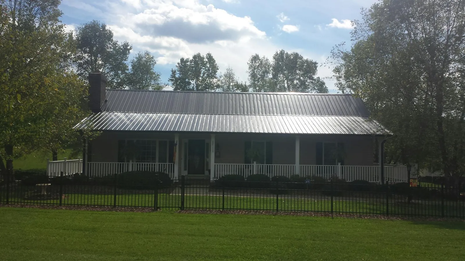 Gray metal roof on a brick ranch with a full width front porch — Gutter Guard Installation work by our crew in Stockdale