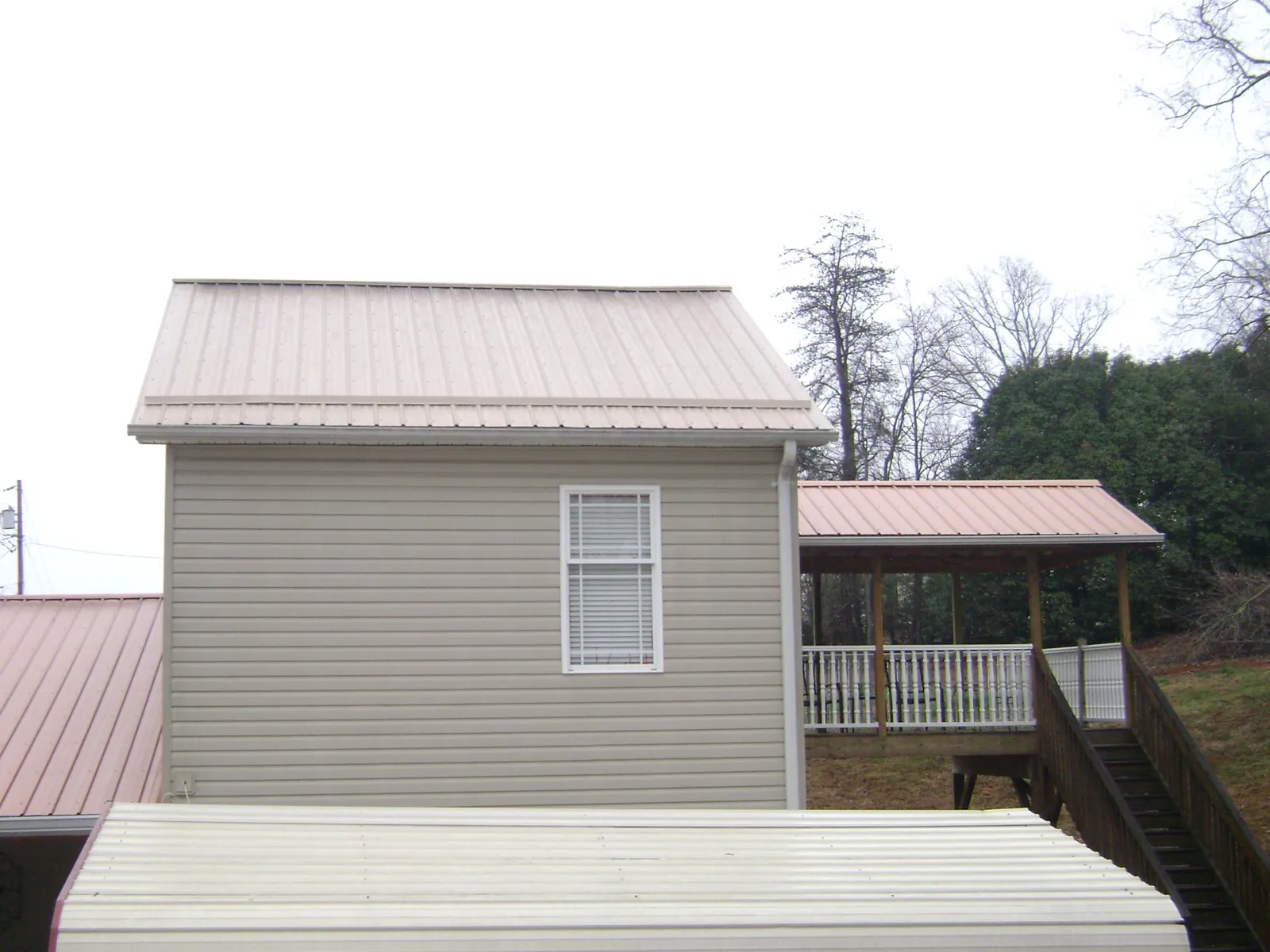 Tan metal roofs on a two story addition and attached porch, from a Roof Replacement job in Stockdale